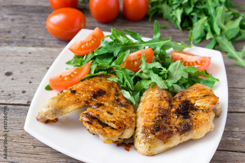 Spicy grilled chicken wings and vegetables  on rustic background.