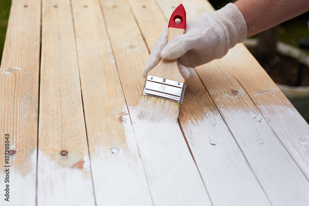 Naklejka premium Man hand with paintbrush painting on a wooden table