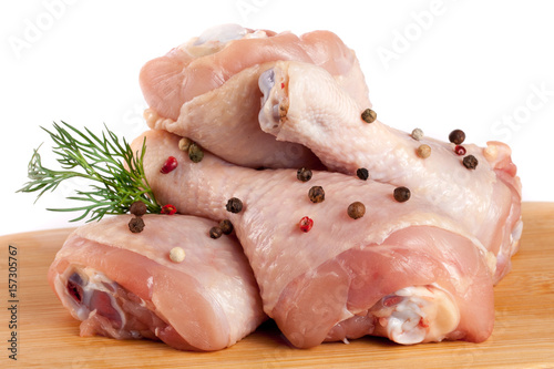 raw chicken drumsticks on a wooden cutting boardn with a sprig of dill and peppercorns white background photo