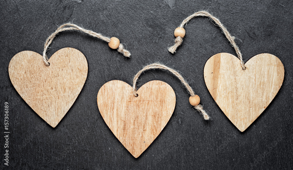 Obraz premium three wooden hearts on a black background. copy space for your text inside the hearts.