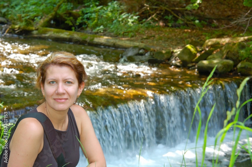 Beautiful woman resting near small waterfall