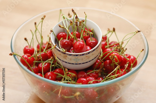 Many cherries lie and dry in a glass bowl and ceramic cup