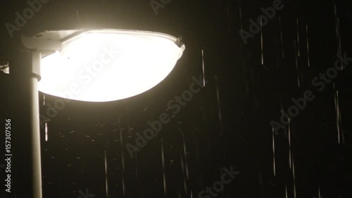 Rainy night and a solitary lamppost. Close up view of raindrops against a lamppost bright light. photo