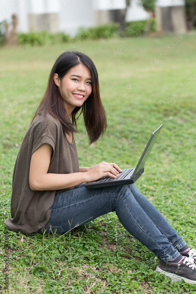 single asian teen smile student using laptop computer with business data working in university.