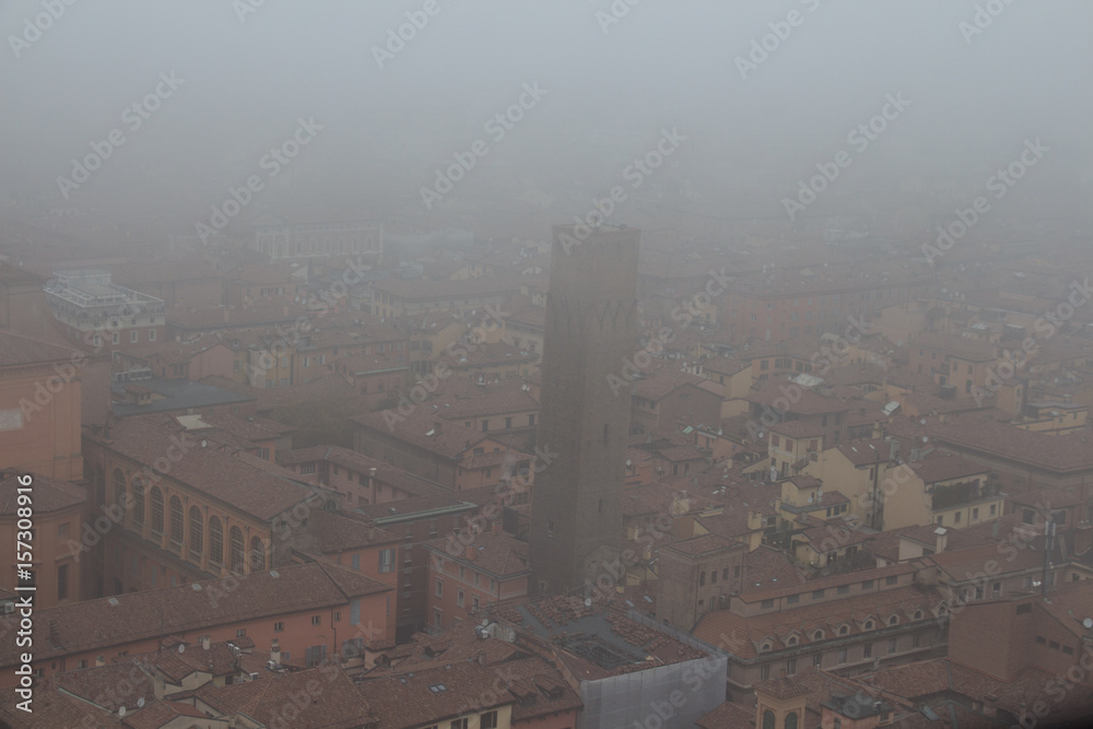 Typical red roofs of Bologna and a tower in a foggy day. View from Asinelli Tower. Emilia Romagna , Italy.