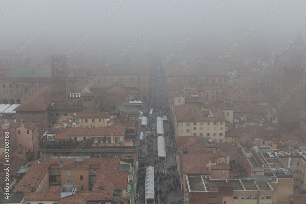 Typical red roofs of Bologna and a market in a foggy day. View from Asinelli Tower. Emilia Romagna , Italy.