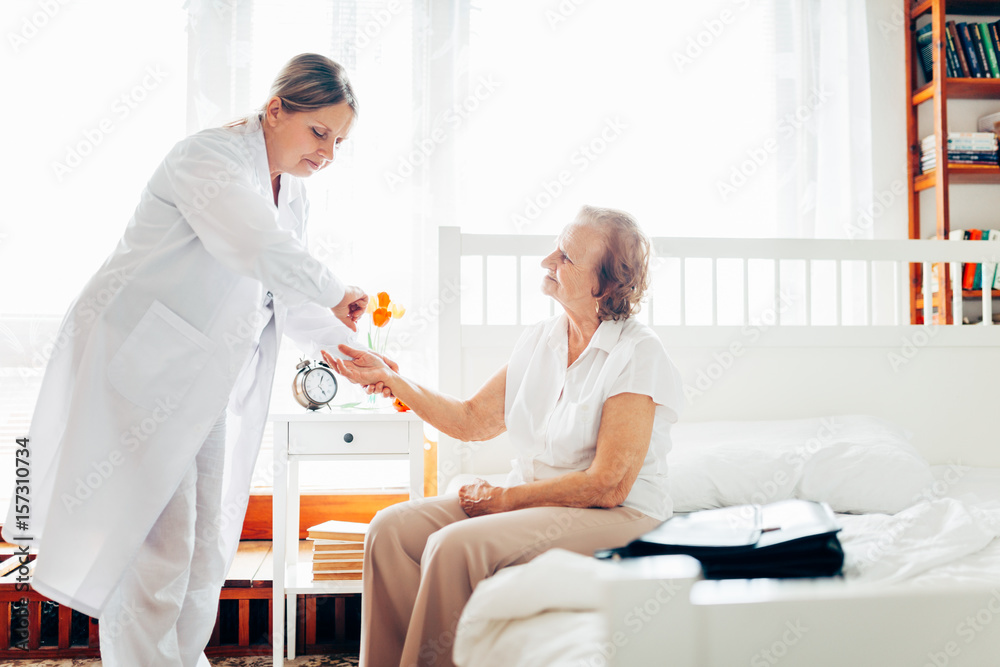 Fototapeta premium Providing care for elderly. Doctor visiting elderly patient at home.