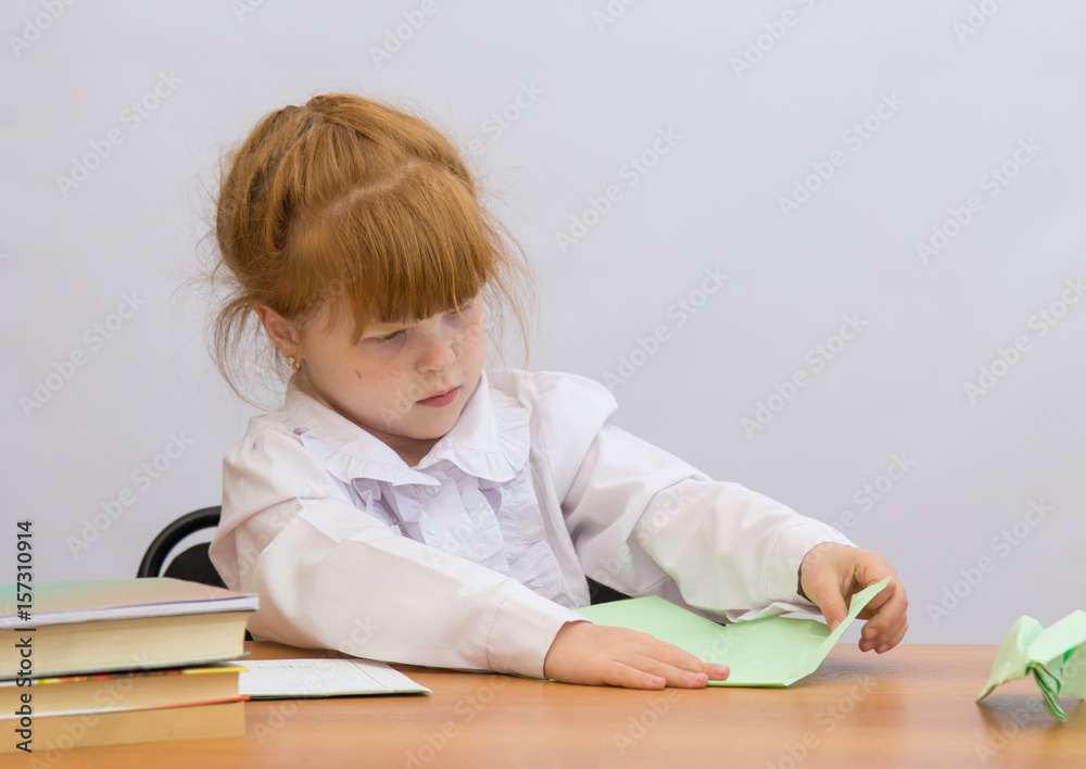 The little girl at the table with concentration makes Paper Airplane