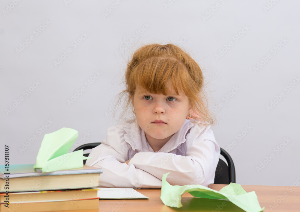 Little girl hurt sitting at table with Paper Airplane Little girl hurt sitting at table with Paper Airplane