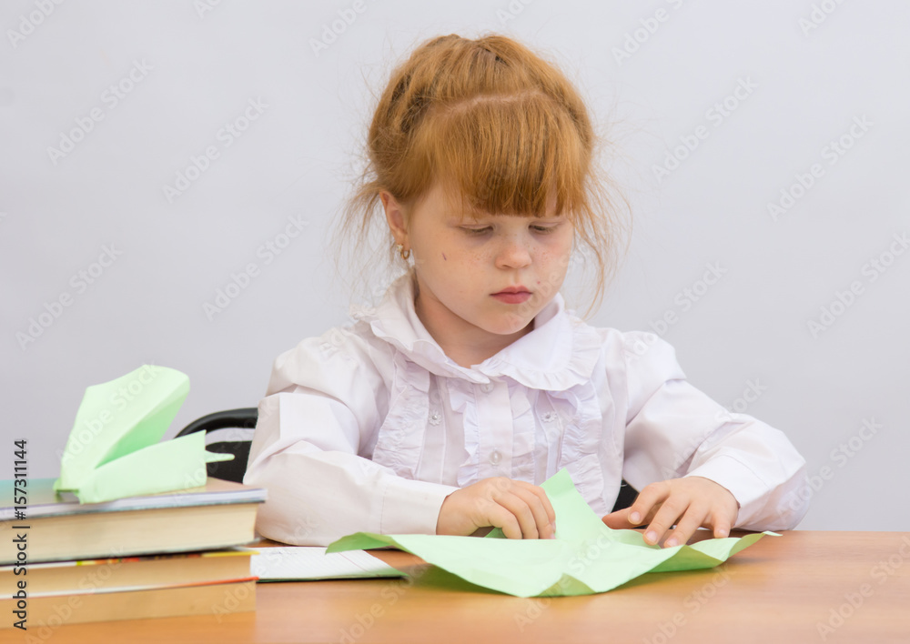 The little girl at the table with concentration makes Paper Airplane The little girl at the table with concentration makes Paper Airplane