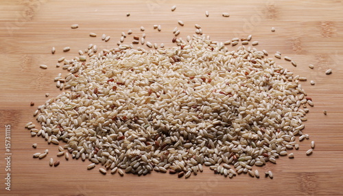 Integral, brown rice pile isolated on wooden table