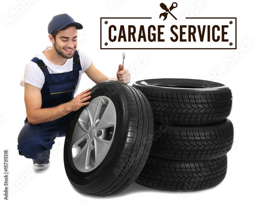 Young mechanic in uniform with wheels on white background