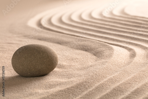 Yoga meditation zen background. Sand texture and round stone. Spa wellness theme.