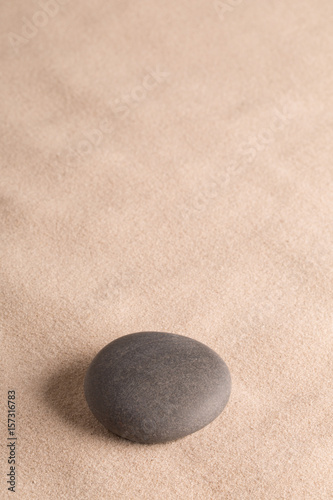round dark stone on sand, minimal zen yoga or spa wellness background with copy space