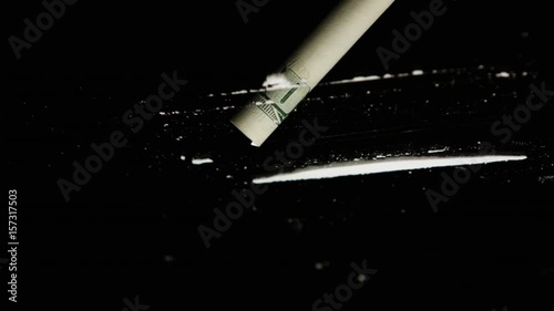 Drug Abuse. A rolled banknote snorting two lines of cocaine powder. Problems with drugs concept. Black background. Close-up macro shot. photo