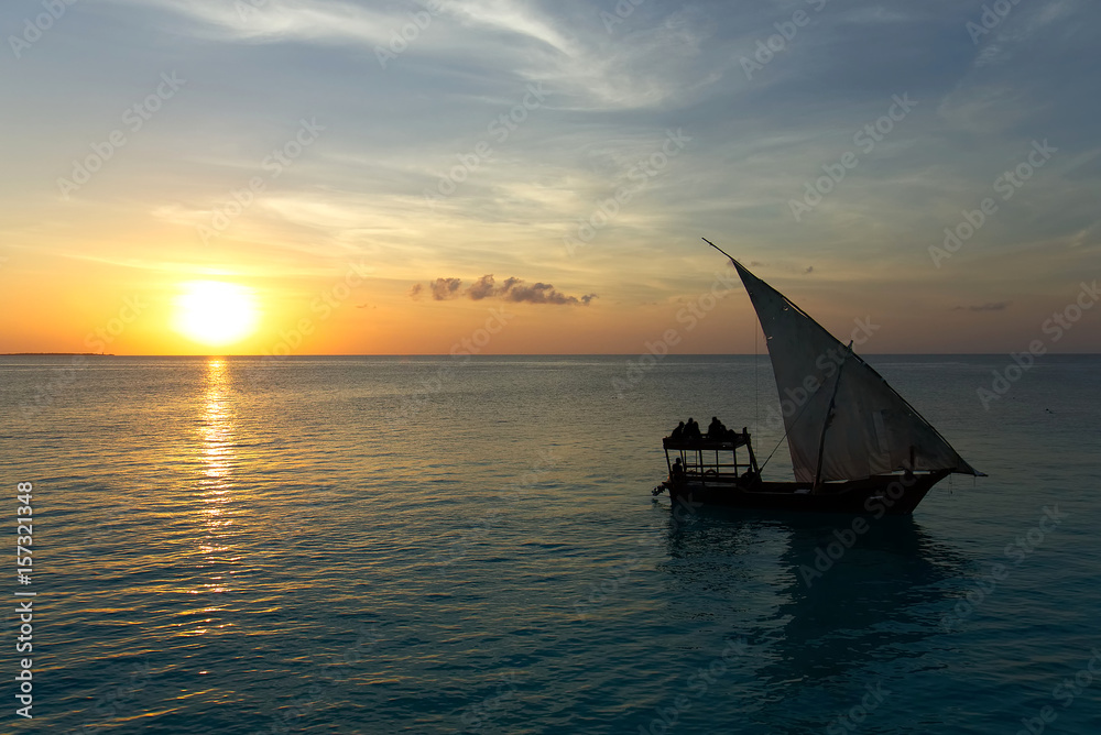 Stunning sunset captured north on Zanzibar, Tanzania, Africa. Sailboat passing by.