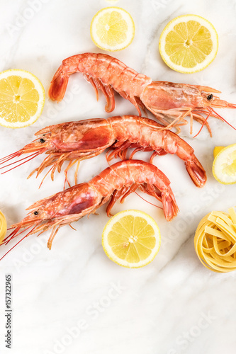 Raw shrimps with lemon and pasta on marble table
