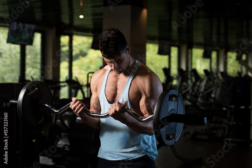 Muscular Man Exercising Biceps With Barbell