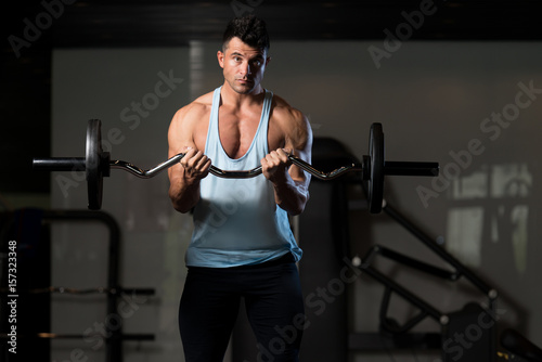 Muscular Man Exercising Biceps With Barbell