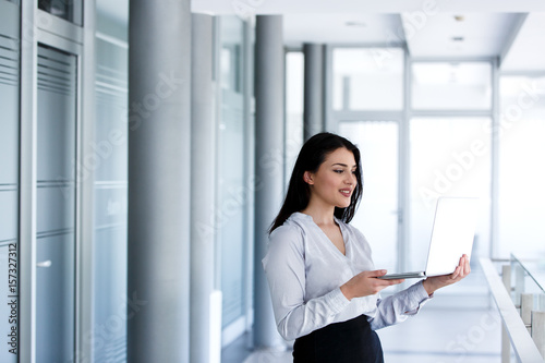 Beautiful business woman standing with laptop in her hand