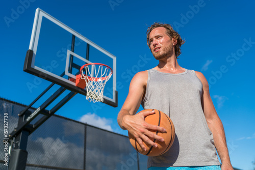 Basketball playing man on court with ball. Athlete player portrait with net in background. © Maridav