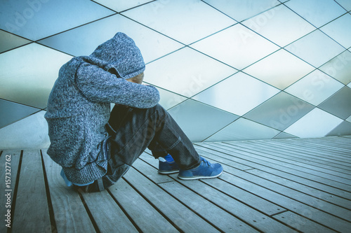 Foto Sad, lonely, unhappy, disappointed child sitting alone on the ground outdoors