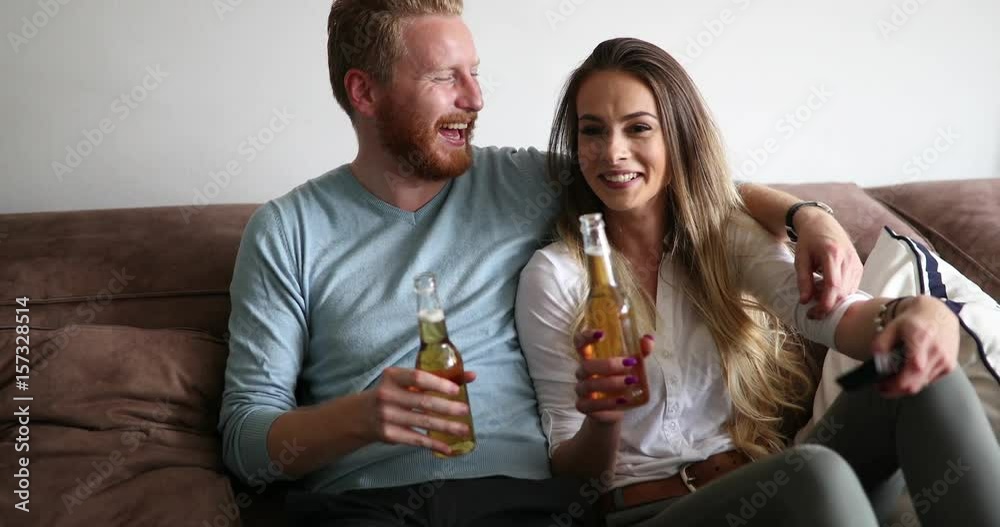 Beautiful couple in love watching tv and drinking Beautiful couple in love watching tv and drinking