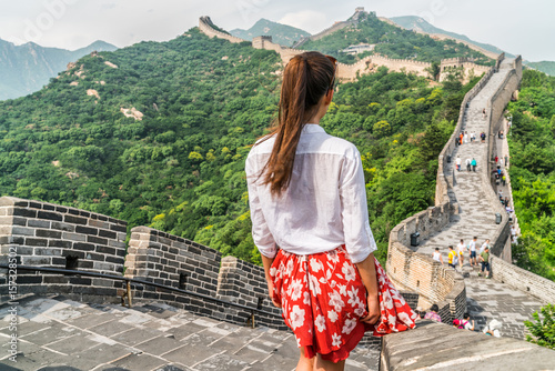 Young girl tourist from behind looking at view of Great Wall of china at famous Badaling tourism attraction during travel vacation in Beijing. Asia summer holidays.
