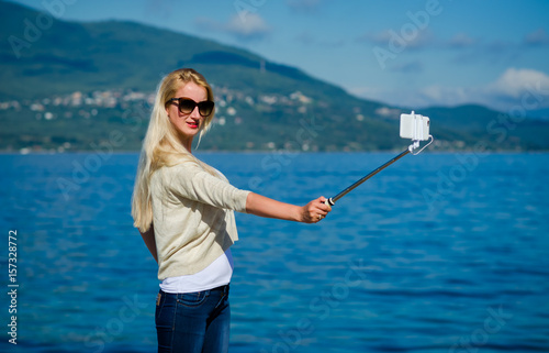 Girl taking mobile photos selfie on background of the island and the sea