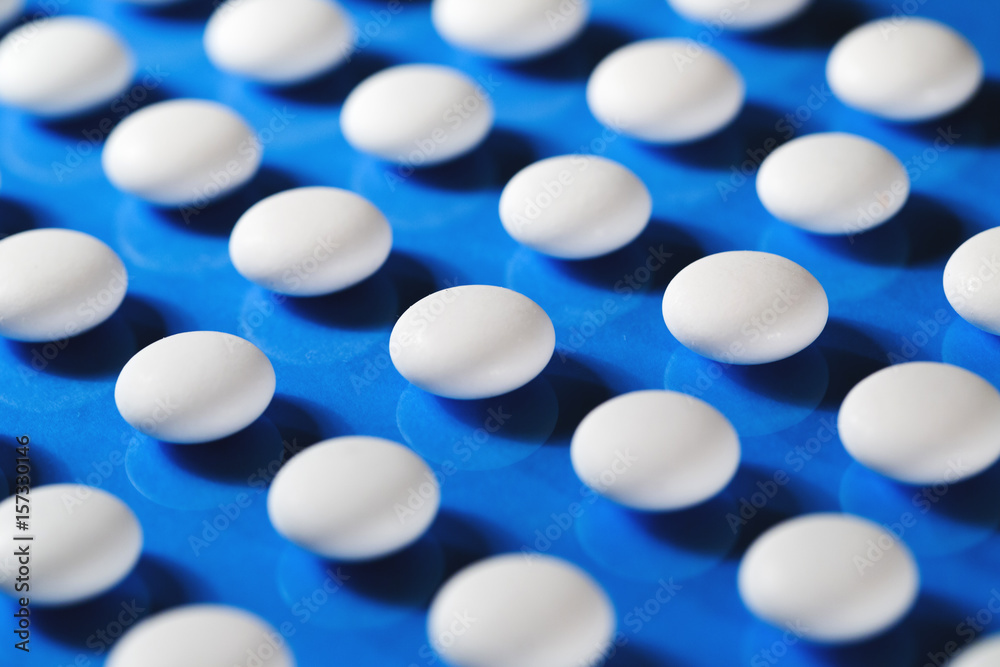White medical pills on blue background. White medical pills on blue background.