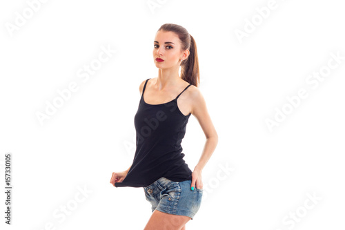 beautiful slim girl with red lipstick in a t-shirt and shorts looking ahead and keeping her hand on the side