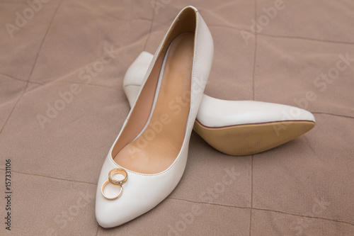 gold wedding rings lie on white shoes photo