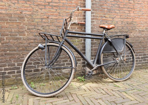 Sturdy black retro style bicycle parked against an ancient brick wall, Amsterdam, The Netherlands