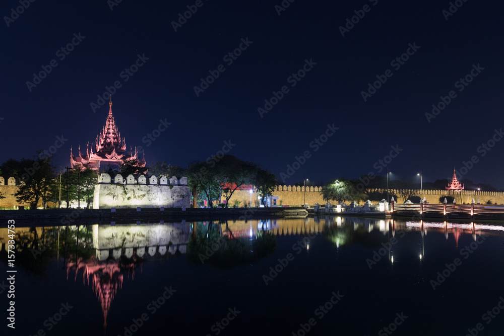 Obraz premium Lit citadel's wall, bastion and pyatthat (spire) and moat at the royal Mandalay Palace in Mandalay, Myanmar (Burma) at night. Copy space.