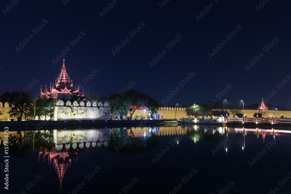 Lit citadel's wall, bastion and pyatthat (spire) and moat at the royal Mandalay Palace in Mandalay, Myanmar (Burma) at night. Copy space.