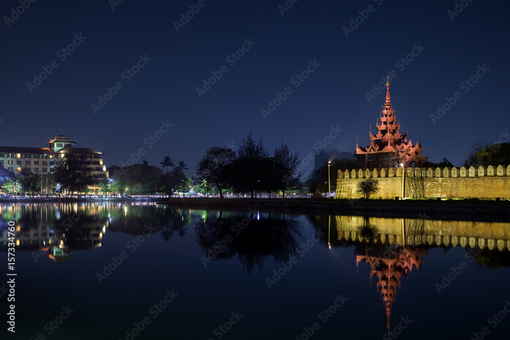 Obraz premium City and lit citadel's wall, bastion and pyatthat (spire) and moat at the royal Mandalay Palace in Mandalay, Myanmar (Burma) at night. Copy space.
