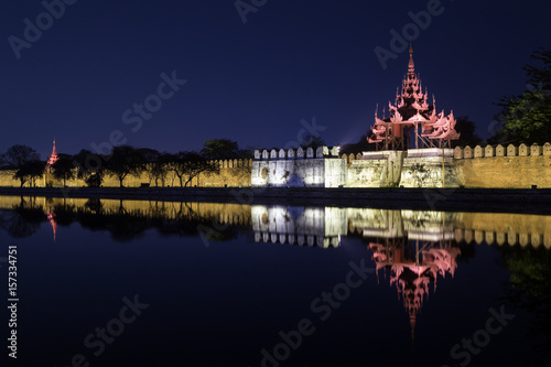 Lit citadel's wall, bastion and pyatthat (spire) and moat at the royal Mandalay Palace in Mandalay, Myanmar (Burma) at night.