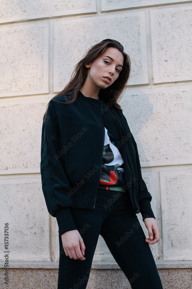 A young and stylish girl in fashionable clothes walks down the street in the city A young and stylish girl in fashionable clothes walks down the street in the city