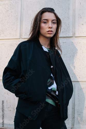 A young and stylish girl in fashionable clothes walks down the street in the city