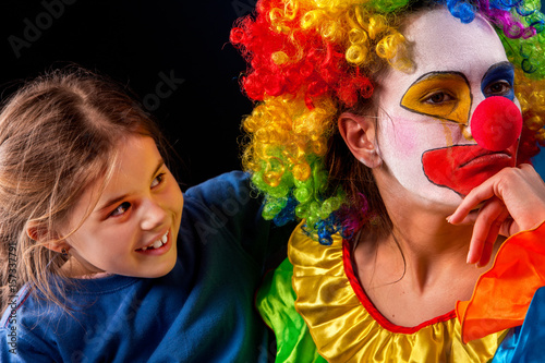 Single parent family. Tired mom after work as clown on birthday on dark background. Mother angry child and girl apology. Adult kid relationship. Social problem mad parent.