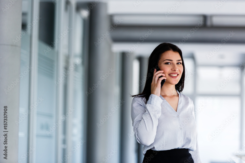 Attractive woman standing while talking on phone in business building Attractive woman standing while talking on phone in business building