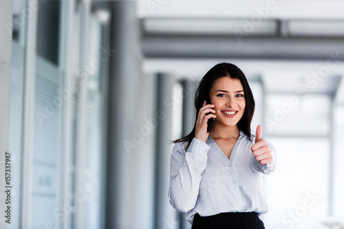 Attractive woman talking on phone and showing thums up