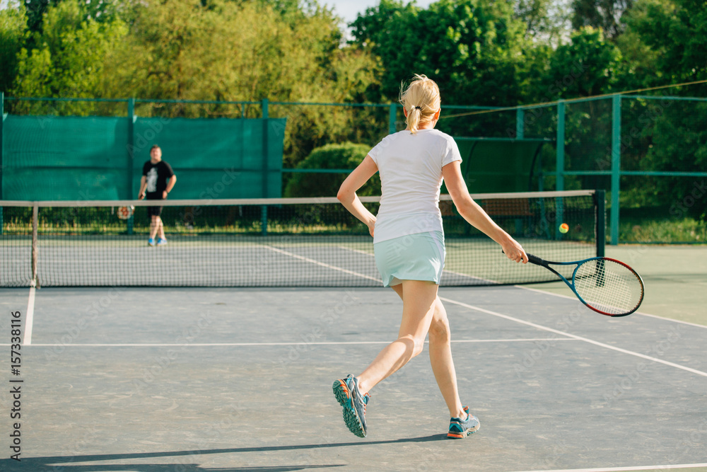 Obraz premium Tennis player playing on the court on a sunny day. Young sport woman training outdoors. Healthy lifestyle concept.