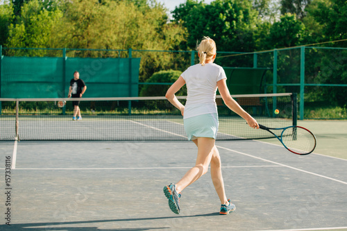 Tennis player playing on the court on a sunny day. Young sport woman training outdoors. Healthy lifestyle concept. © beatleoff