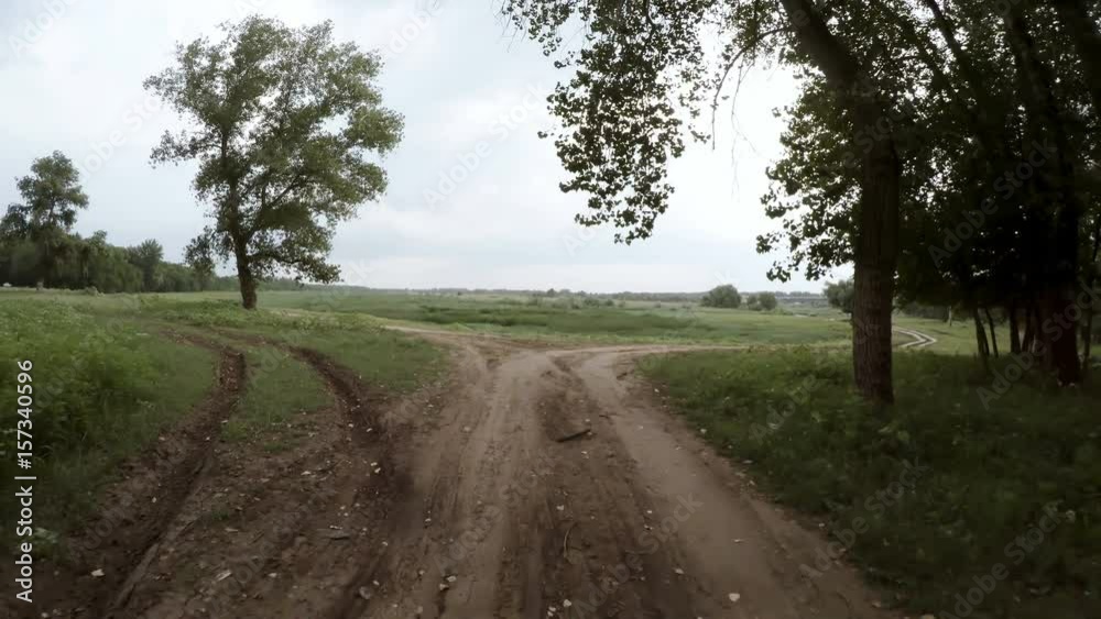 A view of the rural dirt road from camera installed on back of the car driving along this country road. Riding between trees on a rough roadway. A view of the rural dirt road from camera installed on back of the car driving along this country road. Riding between trees on a rough roadway.