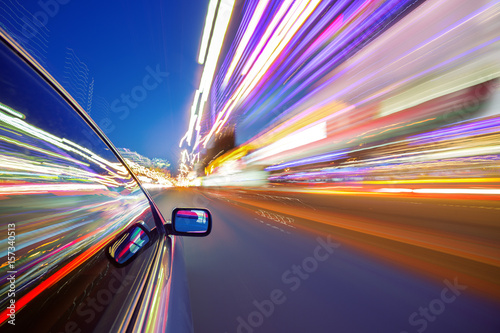 View from Side of Car moving in a night city, Blured road with lights with car on high speed. Concept rapid rhythm of a modern city. 