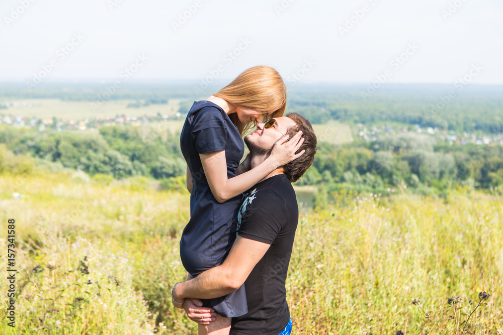 Young couple outdoor portrait. Beautiful pretty girl kissing handsome boy. Sensual photo