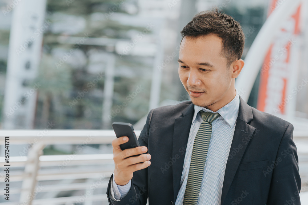 Young Asian businessman using mobile phone outdoor. Young Asian businessman using mobile phone outdoor.