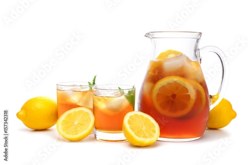Pitcher of iced tea with two glasses and lemons isolated on a white background