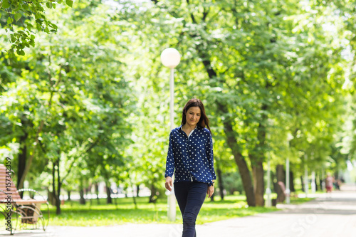 Beautiful young woman walking in green summer park © satura_